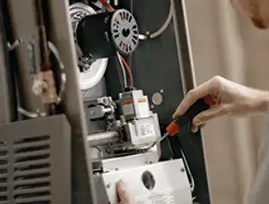 Furnace repair technician inspecting internal components and wiring in Hartford, CT