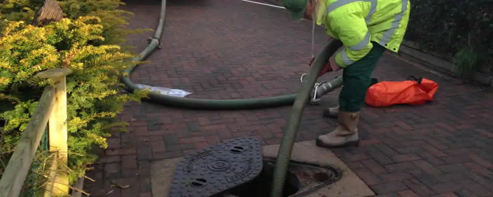 Septic tank cleaning technician servicing a septic tank with a vacuum hose in Hartford, CT