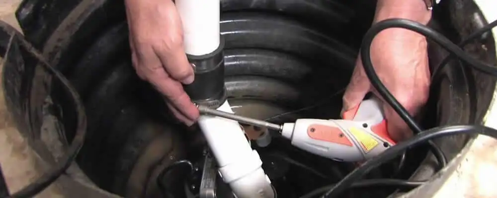 Sump pump installation technician connecting PVC discharge piping in Hartford, CT