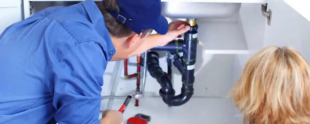 Plumber repairing under-sink drain pipes and fittings in Hartford, CT