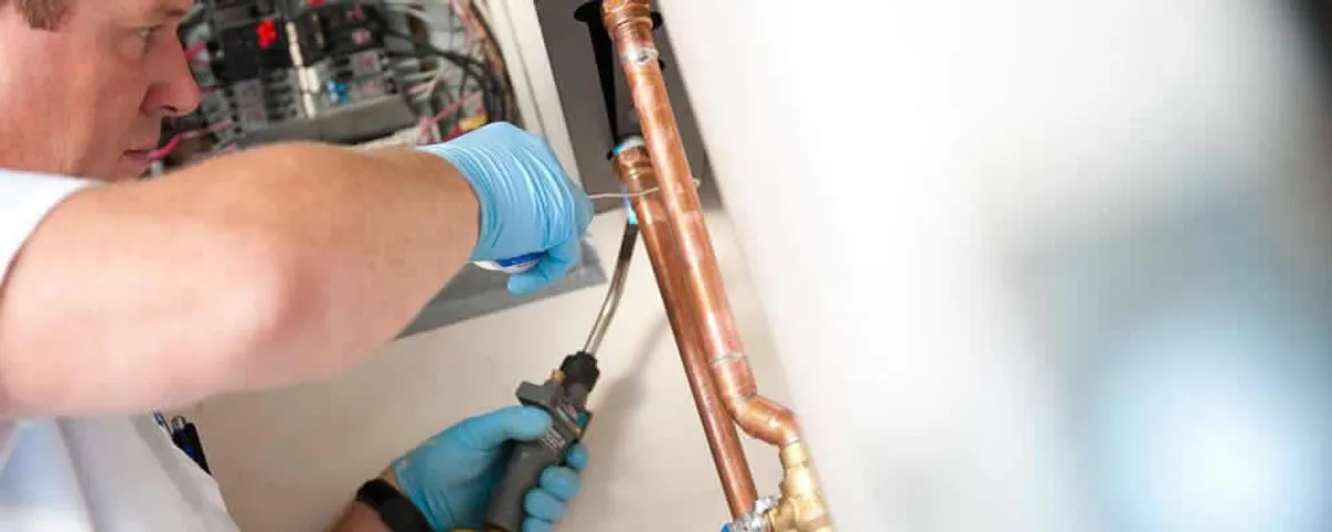 Water heater repair technician testing copper pipe connections and controls in Hartford, CT
