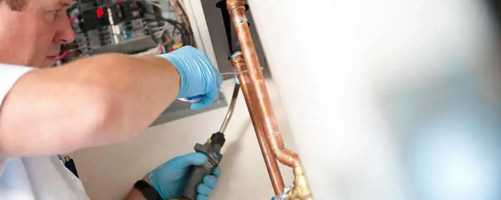 Water heater repair technician testing copper pipe connections and controls in Hartford, CT